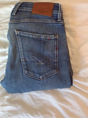 Replay blå - Snygga blå  jeans med klassisk femficksdesign och kontrastsömmar. Jeansen har en läderpatch bak i midjan och diskreta slitningar framtill för en cool look. Tillverkade i mjukt denimtyg som sitter skönt hela dagen.