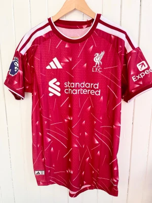 Alexander Isak - Liverpool 2026/2027 - Player version - Liverpools matchtröja för årets säsong 2026/27 med Isak på ryggen. Tröjan är en reprint i nyskick med emblem och patchar av högsta kvalité.   Storlek:XL, men liknar mer L/XL. Denna tröja är en player version, tröjan som spelarna själva använder. Bättre kvalité och passform (slim fit).  Kan skickas snabbt eller hämtas i Majorna i Göteborg.    #fifa #WorldCup #panini #fotboll #fifa #Argentina #panini #fotboll #fashion #Messi #Barcelona #Ronaldo