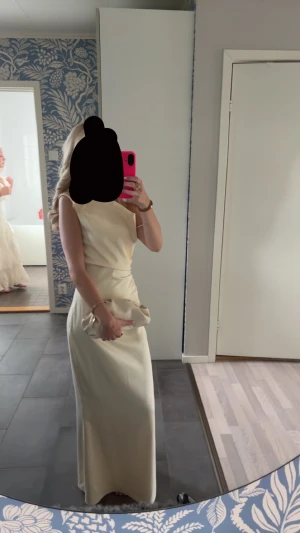 Ljusgul balklänning från adoore   - Elegant långklänning i ljus färg med omlottdetalj i midjan. Klänningen är ärmlös och har en stilren, figurnära passform som ger en klassisk siluett. Perfekt för speciella tillfällen där du vill känna dig extra fin.