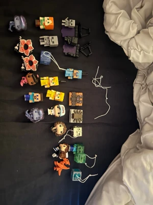 Samling Minecraft och popkulturfigurer - Säljer en samling små figurer och nyckelringar med karaktärer från Minecraft och andra popkulturspel. Figurerna är i olika färger som grön, blå, orange och lila, och är tillverkade i plast. Perfekt för dig som gillar att samla eller dekorera med spelrelaterade prylar.