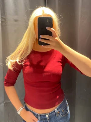 Princess Polly Mörkröd ribbad topp med trekvartsärm - Snygg mörkröd ribbad topp från KappAhl med trekvartsärm och rund halsringning. Perfekt till jeans eller kjol för en enkel men stilren look. Materialet är mjukt och stretchigt för en bekväm passform.