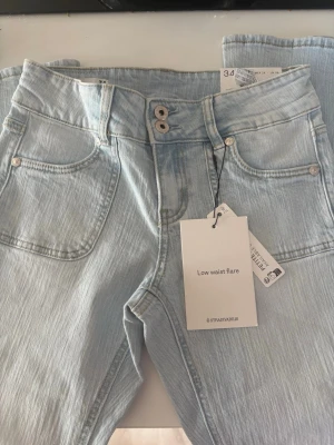Ljusblå low waist flare jeans - Snygga ljusblå jeans från Stradivarius med låg midja och utsvängda ben. Aldrig använda och med prislappen kvar. Super fina!
