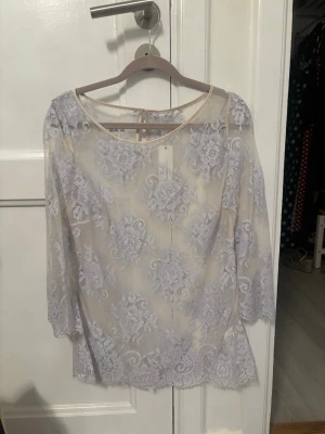 Ny Intimissimi topp - Superfin ljuslila blus i transparent spets med blommigt mönster. Blusen har rund halsringning och trekvartsärmar. Perfekt för dig som gillar romantisk och feminin stil. Materialet är lätt och luftigt, vilket gör den bekväm att bära.