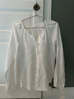 Vit luftig blus med knappar - En stilren vit blus i ett lätt och luftigt tyg med lång ärm och knappar framtill. Blusen har en avslappnad passform och rundad halsringning, perfekt för en trendig och enkel look. Är i barn storlek men skulle säga att den är S-XS