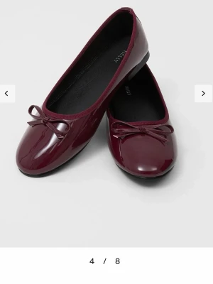 Vinröda lackade ballerinaskor med rosett - Snygga vinröda ballerinaskor i glansigt lackmaterial med en söt liten rosett framtill. Skorna är köpta från Nelly, aldrig använda! Storlek 37