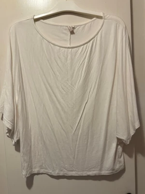 Vit lös topp med vida ärmar - En enkel och stilren vit topp med rund halsringning och vida, lösa ärmar. Tillverkad i mjukt material som känns skönt mot huden. Perfekt för dig som gillar en avslappnad och trendig look.