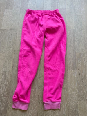 Rosa fleecebyxor från McKinley - Säljer ett par mjuka och sköna rosa fleecebyxor från McKinley. Byxorna har resår i midjan och muddar vid bensluten. Perfekta för chill eller som lager under ytterkläder. Materialet är fleece som håller dig varm och bekväm.