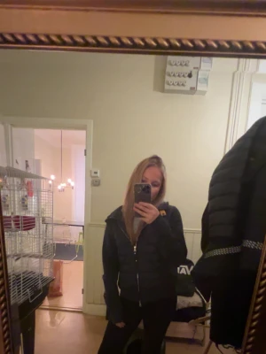 Mörkblå pufferjacka med huva - Säljer en mörkblå pufferjacka med huva och dragkedja framtill. Jackan har quiltad framsida och släta ärmar, samt två fickor med dragkedja. Perfekt för kalla dagar och har en sportig, stilren look.