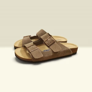 Birkenstock Arizona Taupe  - Snygga Taupe sandaler från Birkenstock i mocka med två breda remmar och justerbara metallspännen. Fotbädden är ergonomisk och sulan är i kork för extra komfort. Perfekta för en avslappnad och trendig stil.