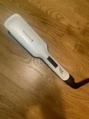 Remington Shine Therapy plattång - En vit och svart plattång från Remington Shine Therapy med digital display och två knappar för tempratur och en av och på.Sladdansluten och har breda plattor, perfekt för att styla håret snabbt och enkelt. Tillverkad i plast och metall. Funkar perfekt men är lite sliten på utsidan❤️