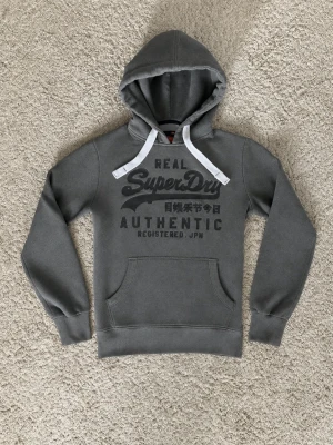 Superdry Hoodie Grå - Superdry Hoodie grå - Storlek: S - Pris: 599kr - Väldigt fint skick och fräsch. - Först till Kvarn!