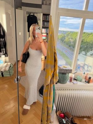 Ljusgrå långklänning med smala axelband - Säljer en stilren ljusgrå långklänning med smala axelband och figurnära passform. Klänningen är ärmlös och har en enkel, clean look som passar perfekt till sommaren. Liknande skins och är köpt från Gina! Klänningen är super skön☀️