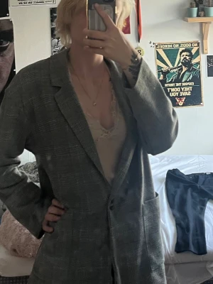 Grå rutig oversized kavaj - Snygg grå kavaj med rutigt mönster och oversized passform. Klassisk krage, två framfickor och enkelknäppning. Har en liten fläck men är nästan inte synlig 
