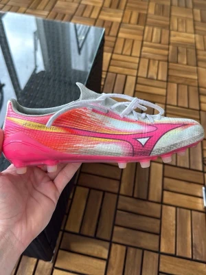 Mizuno Alpha AG Japan - Säljer ett par grymma fotbollsskor från Mizuno i använt skick. Storlek 40,5 (260mm). Skopåse och låda följer med. Lite skönhetsfel men fortfarande mycket sköna att spela i! Säljs ett par Mizuno Alpha FG Elite i mycket bra skick och använda en gång. Också storlek 40,5. 