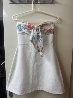 Eftertraktad populär zara klänning  - Supersöt blommig vit miniklänning från zara med en rosett och armlös, den har aldrig använts och har inga defekter🩷🩷
