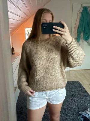 Beige stickad oversized tröja - Mysig beige stickad tröja med oversized passform och rund hals. Tröjan har långa ärmar och är gjord i ett tjockare garn som ger en avslappnad och trendig look. Perfekt att styla med jeans eller kjol för en chill vibe.