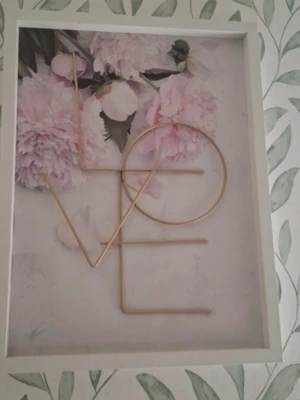 Tavla med LOVE och pionmotiv - Snygg tavla med vit ram, motiv av ljusrosa pioner och texten LOVE i guldmetall. Perfekt som dekoration i hemmet för en romantisk och modern känsla. Bakgrunden är ljus med blommor och texten är tredimensionell.