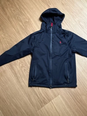 Ralph lauren vindjacka - En snygg ralphlsueen jacka.  Innersmnön vid händerna på både höger och vänster har gått upp som man ser på bild 7 annars i väldigt bra skick storlek XS men kan passa S. Det är en liten tjockare vindjacka 