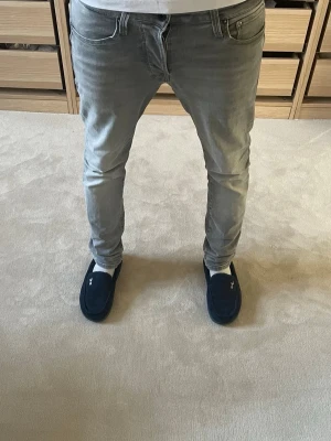 Gråa Jack&Jones jeans - Säljer ett par supersnygga jack&jones jeans i passformen slim fit. Jeansen har en mjuk grå färg med en klassisk femficksmodell. Perfekt för dig som söker en trendig byxa!💫