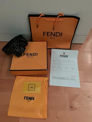 Svart och brunt Fendi bälte med F-logga - Säljer ett svart och brunt bälte från Fendi med det klassiska FF-logomönstret. Exmtremt bra skick knappt använt. Bara att skriva vid andra funderingar!!
