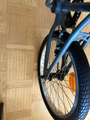 Grå bmx cykel - Säljer en grå cykel med robust ram, grova svarta däck och silverfärgade ekrar. Cykeln har V-bromsar och en orange reflex på bakhjulet. Passar perfekt för ett barn allt fungerar på dne fast att ena bromsen fungerar knappt och den andra fungerar men e seg säljer den för 500kr kan inte fraktas bara vid upphämtning.