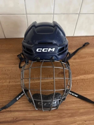 Marinblå CCM hockeyhjälm 720, Storlek M, med galler - Marinblå CCM hockeyhjälm 720 storlek M. Den är knappt använd. Det ända är att alla klistermärken är borttagna och TACKS märket i hjälmen är borta. Rek pris: 2499kr Pris kan diskuteras.  Ishockey, hockeyhjälm, CCM, blå