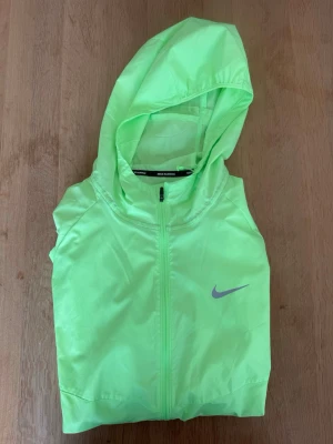 Neongrön löparjacka från Nike - Snygg och ovanlig färg, storlek M, endast använd en gång så jackan är i princip ny! Nypris ligger på runt 1000kr.