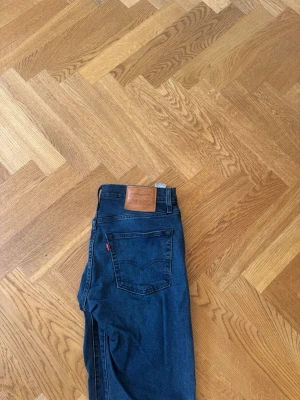 Mörkblå raka jeans från Levi's 512 - Säljer ett par klassiska mörkblå jeans från Levi's med raka ben och femficksmodell. Jeansen har en brun läderpatch bak i midjan och den ikoniska röda Levi's-taggen på bakfickan. Tillverkade i slitstark denim med snygg tvätt. 512, storlek 30 34! Använda enstaka gång!