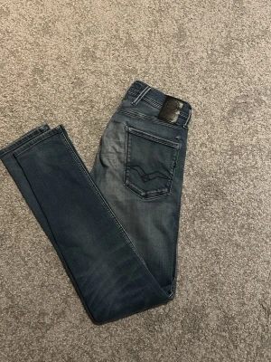 Slim fit replay jeans - Säljer ett par mörkblå slim fit jeans med snygg slitning och diskret detalj på bakfickan. Jeansen har klassisk femficksdesign och är tillverkade i stretchigt denimtyg för skön passform. Perfekta till en avslappnad look. Använda bara ett par fåtal gånger. Slitning syns på bild 2. Skriv om ni har några funderingar!🔥🙏