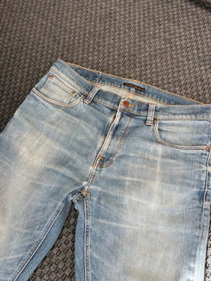 Ljusblå raka jeans med slitningar - Säljer ett par ljusblå jeans med raka ben och snygga slitningar. Jeansen har klassisk femficksmodell, kontrastsömmar och detaljer på bakfickorna. Perfekta för en avslappnad och trendig look.