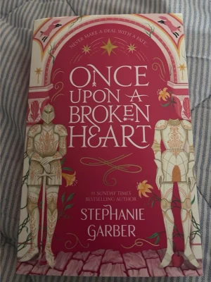 Once Upon a Broken Heart bok - Säljer boken 'Once Upon a Broken Heart' av Stephanie Garber. Omslaget är rosa med detaljer i guld, vitt och grönt samt illustrationer av riddare och blommor. Perfekt för dig som gillar romantisk fantasy och magi. Rekommendera starkt! Säljer då jag måste göra plats i min bokhylla 💕