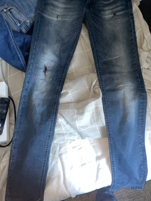 Mörk blåa Jack n Jones - !Vet ej storleken står ej passar mig o är 180 men de är lite för små!    Snygga blå jeans med tydliga slitningar och ljusare partier på låren och knäna. Jeansen har klassisk femficksdesign och normal midja. Perfekta för en avslappnad och trendig look.