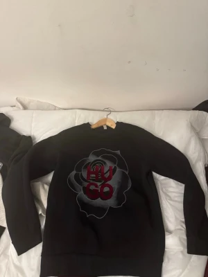 Hugo tröja med blommor - Svart Hugo tröja med blomm detalj. Unik hoodie med bra passform som dessutom går ihop med allt. 