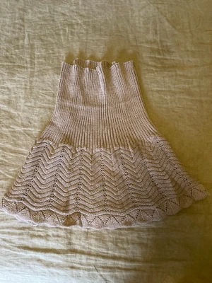 Gammaldagsrosa/lillaktig  stickad halskrage med mönster - Gammaldagsrosa/lillaktig stickad halskrage i mjukt ull garn med ribbad hals. Nedre delen har ett snyggt zickzackmönster som ger en trendig touch. Perfekt att bära över en tröja för extra värme och stil. Materialet känns mjukt och följsamt.