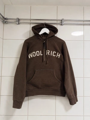 Woolrich hoodie strorlek M  - Woolrich Hoodie Half-Zip – Brun – Storlek M   Storlek: M Färg: Brun Skick: Fint begagnat skick Nypris: Liknande Woolrich-hoodies ligger ofta runt 2 000–3 000 kr nya.  . Säljs till ett bra pris för snabb affär.