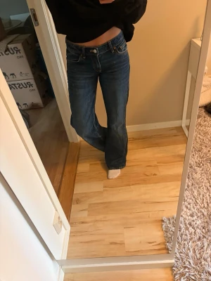 Mörkblå jeans från Zara - Säljer ett par mörkblå jeans med låg midja från Zara. Jeansen har en lätt utsvängd passform nedtill och stängs med knapp och dragkedja. Aldrig använda så är i mycket fint skick. 