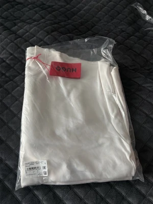 Vit långarmad tröja från Hugo boss - Stilren vit långarmad tröja från Hugo boss, helt oöppnad och i suveränt skick. Plagget är tillverkat i mjukt material och känns väldigt skönt att ha på sig. 
