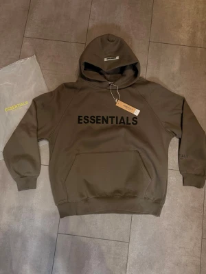 Fear of God Essentials Hoodie Grå - Hoodie från Fear Of God, riktigt tjock och bra material. Helt ny, oanvänd med tags. Hör av dig vid fler frågor!