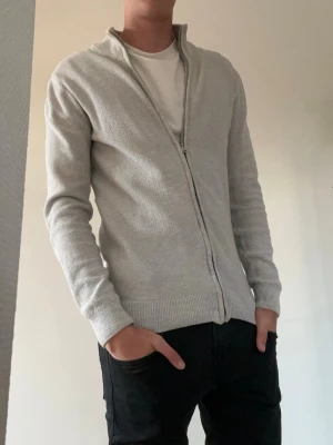 Ljusgrå fullzip - Tjena!👋 Säljer denna ljusgrå stickad ziptröja från INDICODE med ståkrage och hel dragkedja framtill i storlek S🤩 Tröjan har ribbade muddar vid ärmslut och nederkant, och är tillverkad i ett mjukt, tunt material😮‍💨 Perfekt för lager-på-lager och enkel att matcha😌 Meddela vid frågor!📩