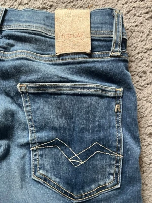 Blå jeans från Replay - Säljer ett par klassiska blå jeans från Replay med snygga kontrastsömmar och unik bakficka med broderad detalj. Jeansen har normal midja och raka ben, perfekta till vardagslooken. Tillverkade i mjukt denimtyg för skön passform.