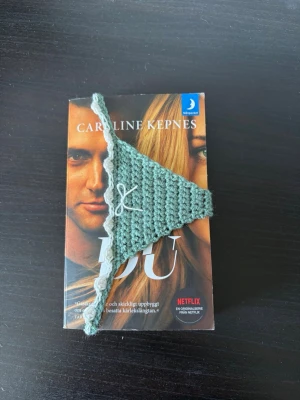 Grönt virkat bokmärke  - Ett bokmärke i form av en trosa med spetskant och en liten rosett framtill 