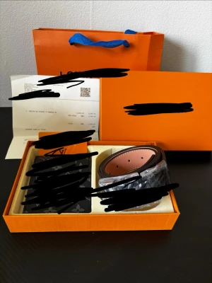 Brunt skärp med svart spänne - Snyggt brunt bälte med svart spänne, levereras i original orange ask. Bältet har klassisk design och passar perfekt till jeans eller kostymbyxor. Kommer med tillhörande förpackning och kvitto.