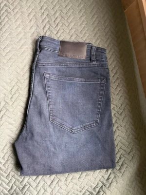 Blå jeans från These Glory Days - Säljer ett par klassiska blå jeans från These Glory Days. Jeansen har rak passform, fem fickor och bälteshällor. Materialet är mjukt denim i en mellanmörk tvätt som passar till det mesta. Perfekta för en avslappnad och stilren look.