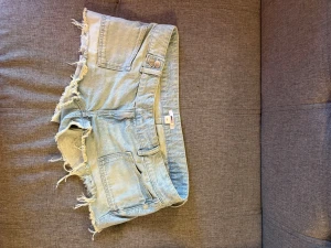 Ljusblå jeansshorts - Ett par ljusblå jeansshorts med fransiga kanter och femficksdesign.