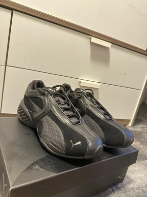 Svarta Puma Cell 1 - Säljer ett par svarta Puma Cell 1 sneakers. Skorna har mesh och mockadetaljer, samt en chunky sula med vågig struktur. Klassisk Puma-logga på sidan och snörning framtill. Helt nya, Ny pris 1850kr (priset kan diskuteras)