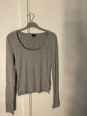 Grå långärmad topp med rund hals - En enkel och stilren grå långärmad topp med rundad urringning. 