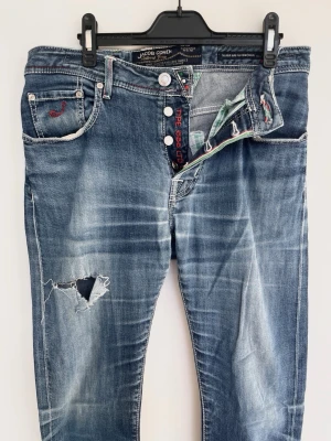 Jacob Cohën Jeans - Jacobcohen jeans med galet fet fade! Fint skick, slitngarna är för design. Storlek 32. Midja=42, Längd=108. Kontakta mig för fler frågor och funderingar!