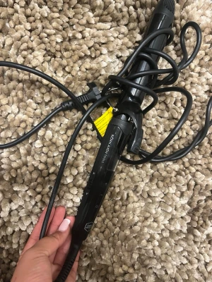 Svart locktång från GHD - Säljer en svart locktång från GHD med digital display och temperaturkontroll. Tången har en sladd med EU-kontakt och är tillverkad i plast och metall. Perfekt för att fixa snygga lockar snabbt och enkelt.