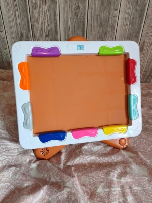 Rittavla stativ spelar musik Kidz Delight Infini Fun Xylopad - Säljer en magisk ritplatta från Infini FUN med vit ram och färgglada knappar runt om i lila, grön, röd, orange, blå, rosa, gul, turkos och silver. Plattan har en orange yta att rita på och står på orange ben. Perfekt för kreativa stunder och lek. Rittavla med stativ som spelar musik när barnet nuddar de färgade delarna. Man sätter in vanliga A4 papper som man ritar på.   Kidz Delight Infini Fun Xylopad  Material Plastic Item dimensions L x W x H 34.3 x 5.1 x 31.8 centimetres Draw to play music: