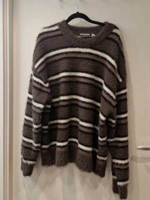 Gråbrun randig oversize tröja - Fluffigt mjukt material. Oversize i storleken. Säljer då den ej kom till användning. Nypris över 600kr.